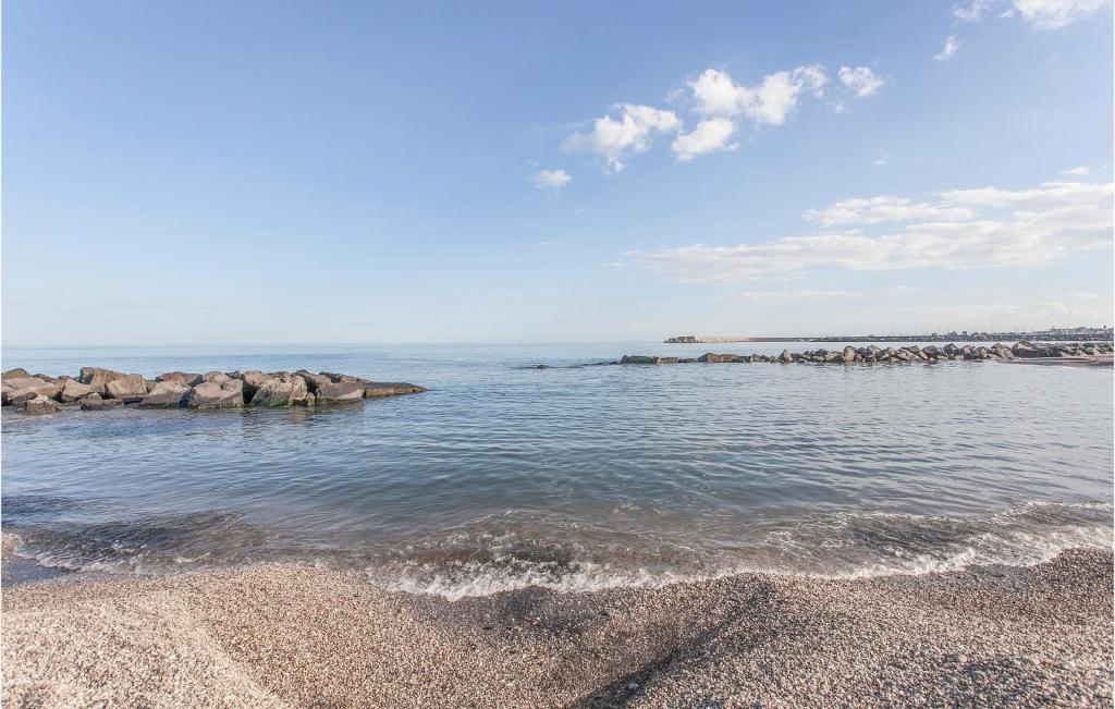 a beach with rocks in the water on a sunny day at Amazing Apartment In Piedimonte Etneo With 2 Bedrooms And Wifi in Piedimonte Etneo