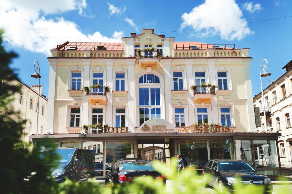 a large white building with cars parked in front of it at Artis Centrum Hotels in Vilnius