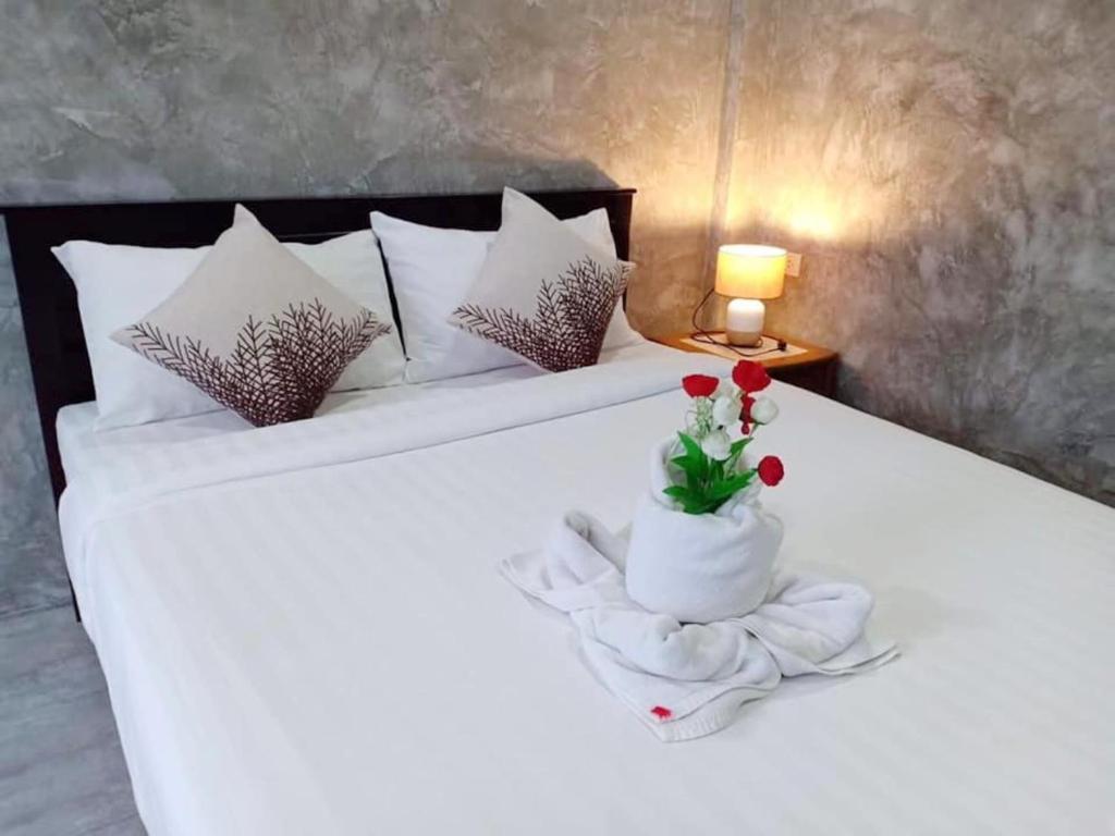 een slaapkamer met een wit bed en een vaas met bloemen bij Lanta smile inn in Koh Lanta