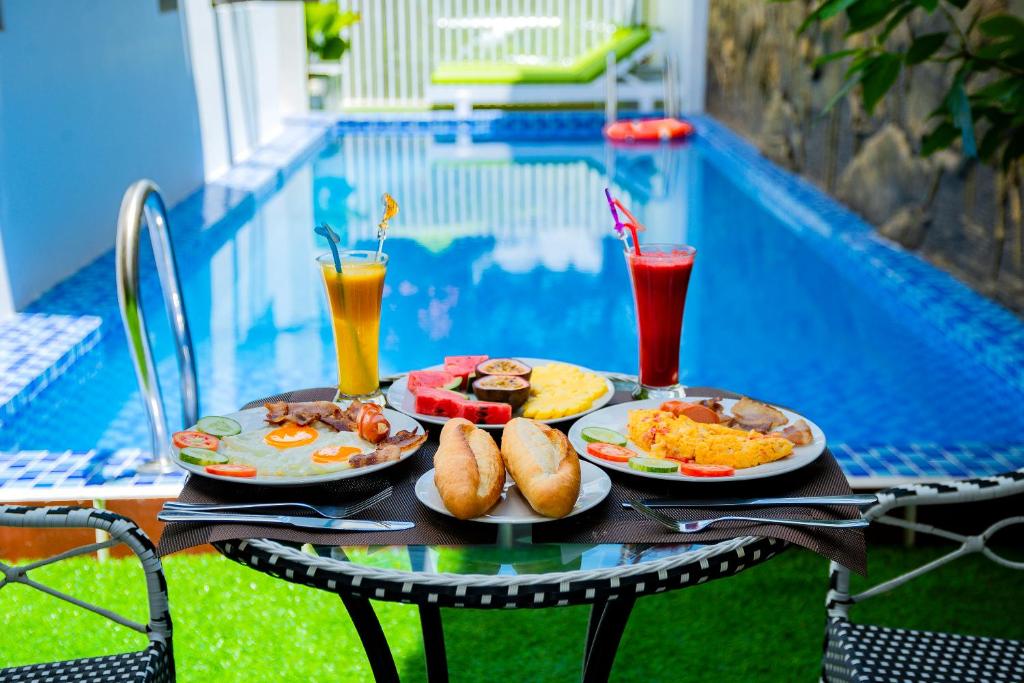 two plates of food on a table next to a pool at Green Hill Hotel in Hoi An