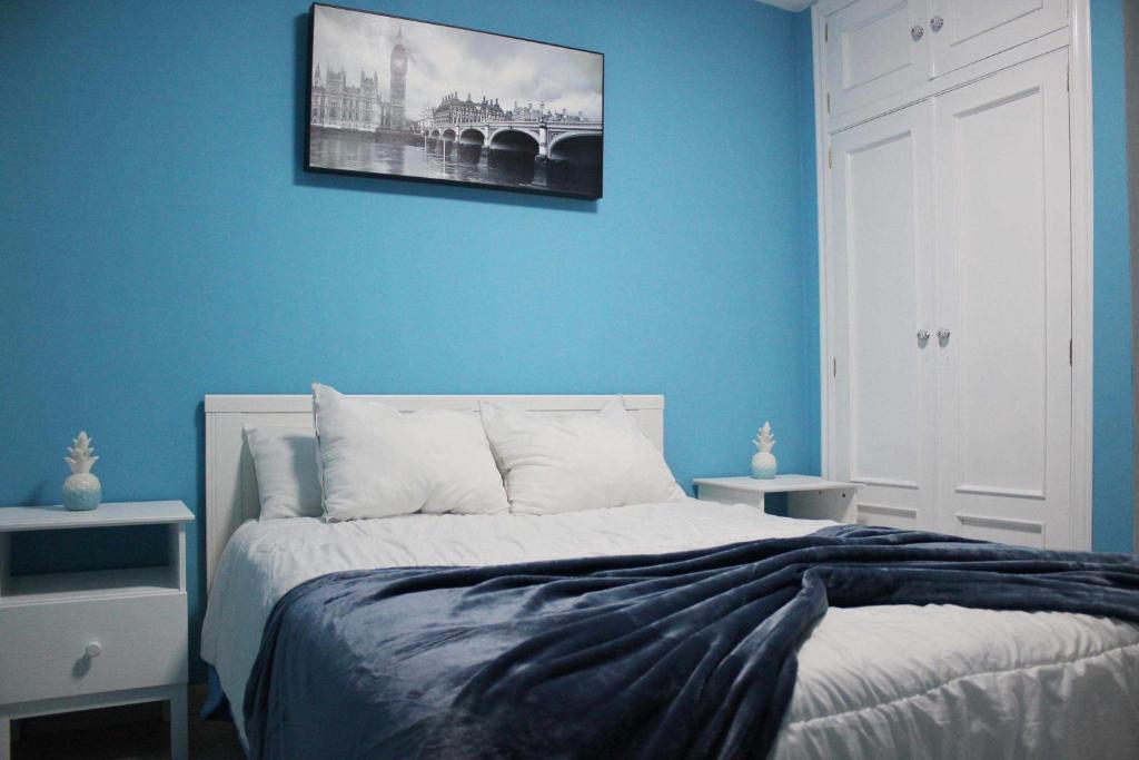 1 dormitorio con una pared azul y 1 cama en El PISO MAS CÉNTRICO DEL HUMEDO DESAYUNO INCLUIDO, en León