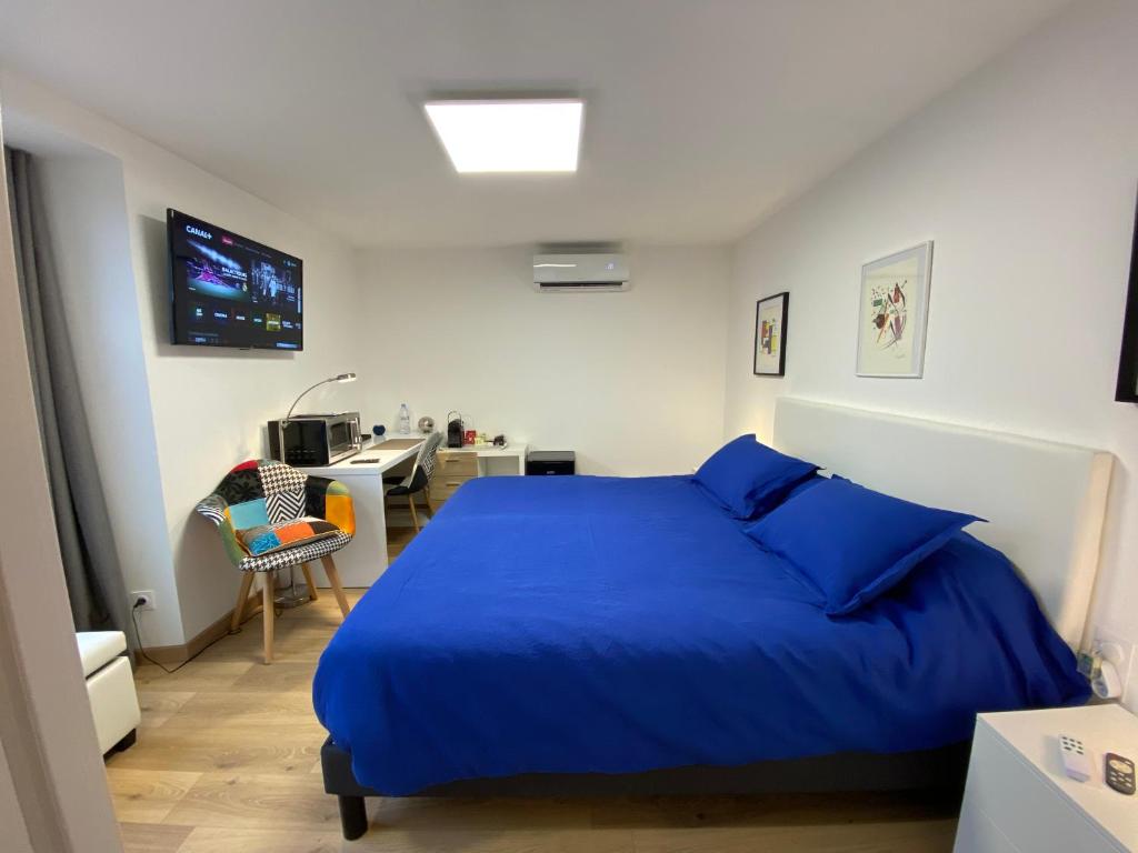 a bedroom with a blue bed and a desk at Chambre d'hôtes indépendante de Pouzatel proche Bonaguil in Fumel