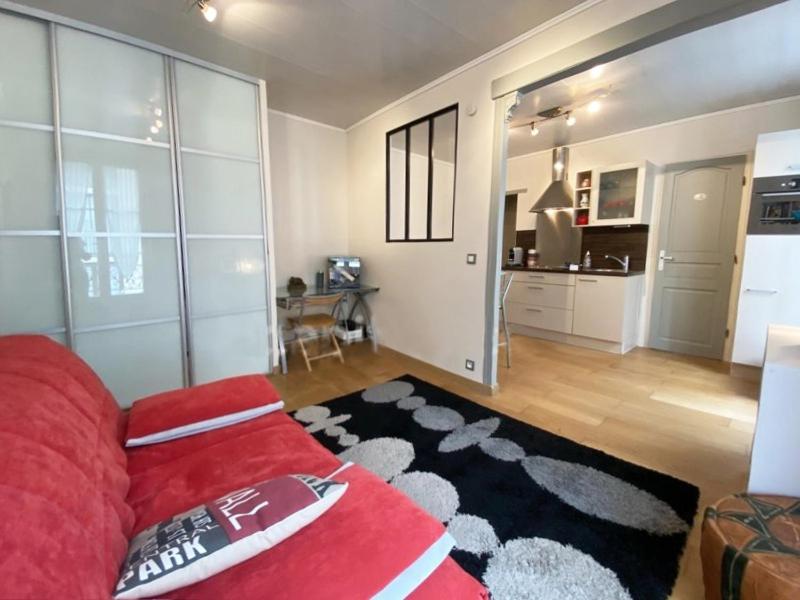 a living room with a red couch and a kitchen at Appartement coquet sur les hauteurs de Montmartre in Paris