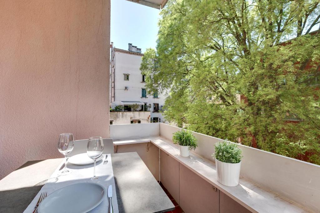 un balcón con 2 copas de vino y una ventana en Priuli Apartment en Venecia