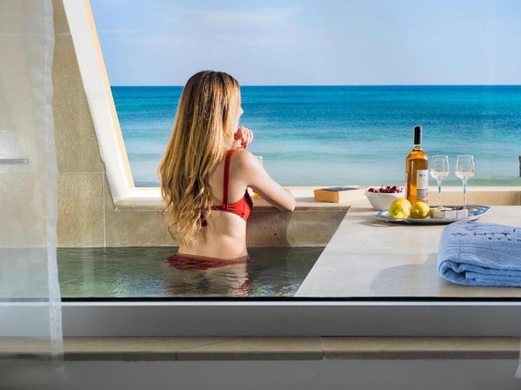 a woman sitting in a bath tub with a view of the ocean at White Bay in Fontane Bianche