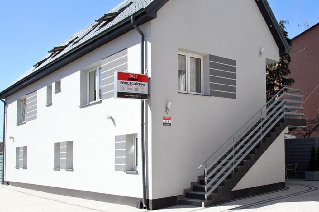 a white building with stairs on the side of it at Ekonomiczne Pokoje Gościnne Dask Holiday in Łeba