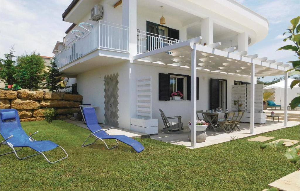 una casa bianca con due sedie blu nel cortile di 2 Bedroom Gorgeous Apartment In Sciacca Ag a Sciacca