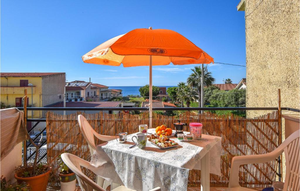 einen Tisch mit einem orangenen Regenschirm und einem Teller mit Essen in der Unterkunft 2 Bedroom Gorgeous Apartment In Trappeto in Trappeto