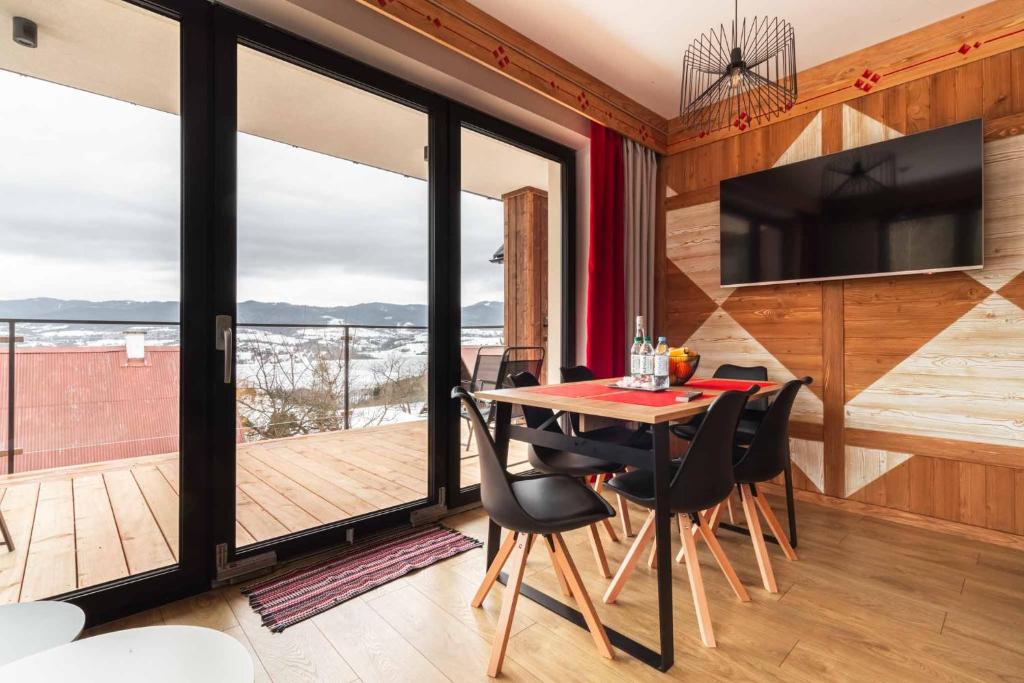 ein Esszimmer mit einem Tisch und Stühlen sowie einem Balkon in der Unterkunft FAJNE CHATY - rodzinny wypoczynek w górach in Falsztyn