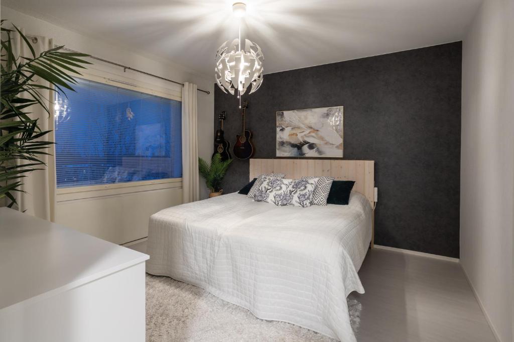 a bedroom with a white bed and a chandelier at Modern design w/balcony, free parking,WiFi & A/C in Lappeenranta