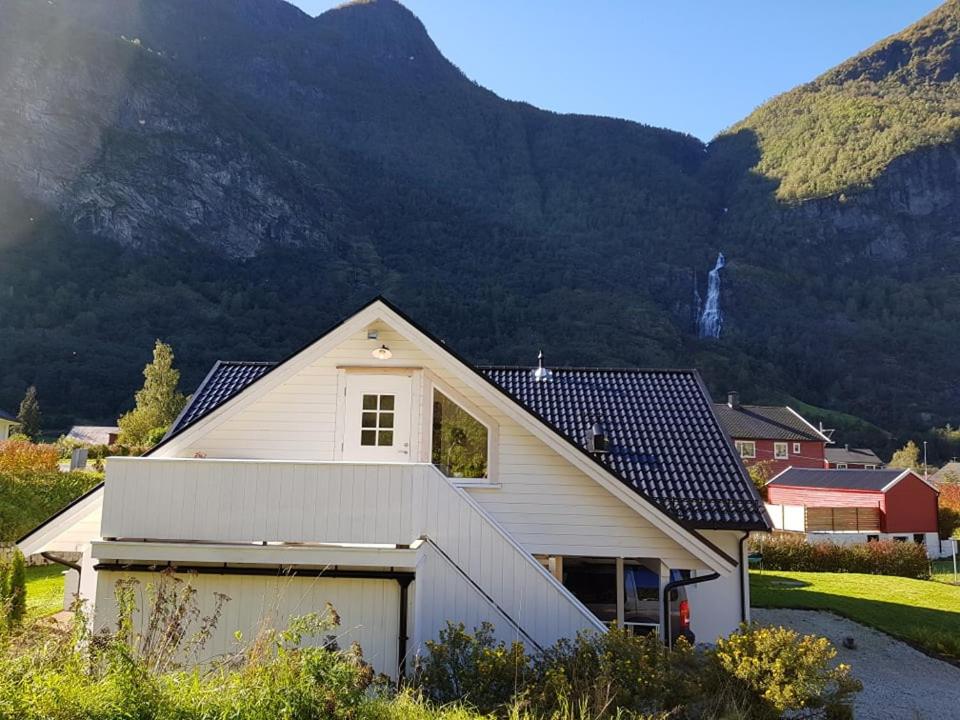 una casa bianca con un garage di fronte a una montagna di Bright and cozy apartment 1.5km from city centre ad Aurland