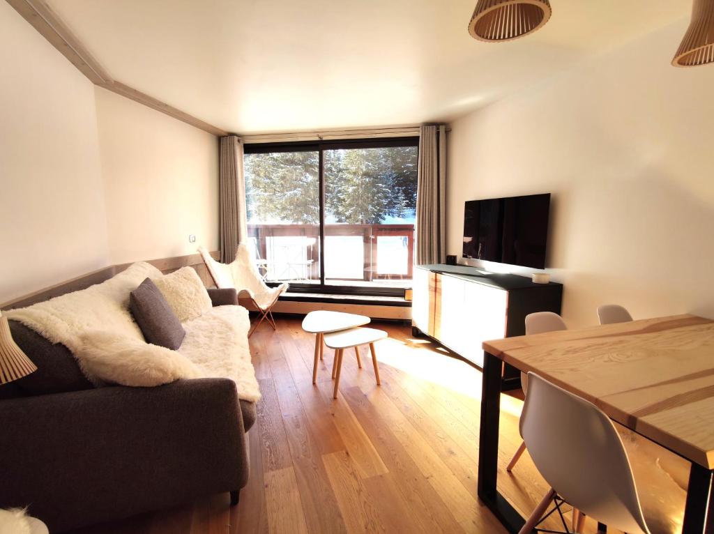 a living room with a couch and a table at Douglas - Appartement au cœur du Jardin Alpin in Courchevel