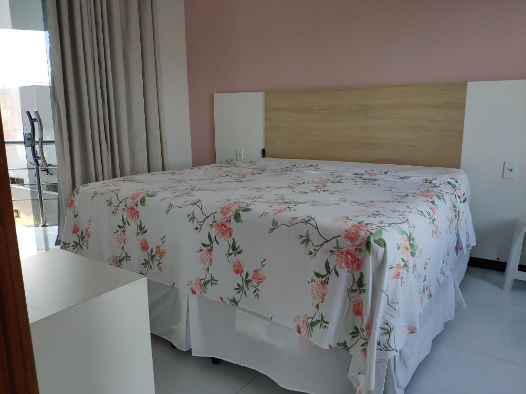 a bedroom with a bed with a floral bedspread at Casa Porto Di Nassau in Porto Seguro