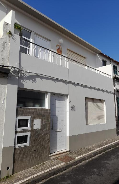 a white building with a door and a balcony at Upstairs Home in Ponta Delgada