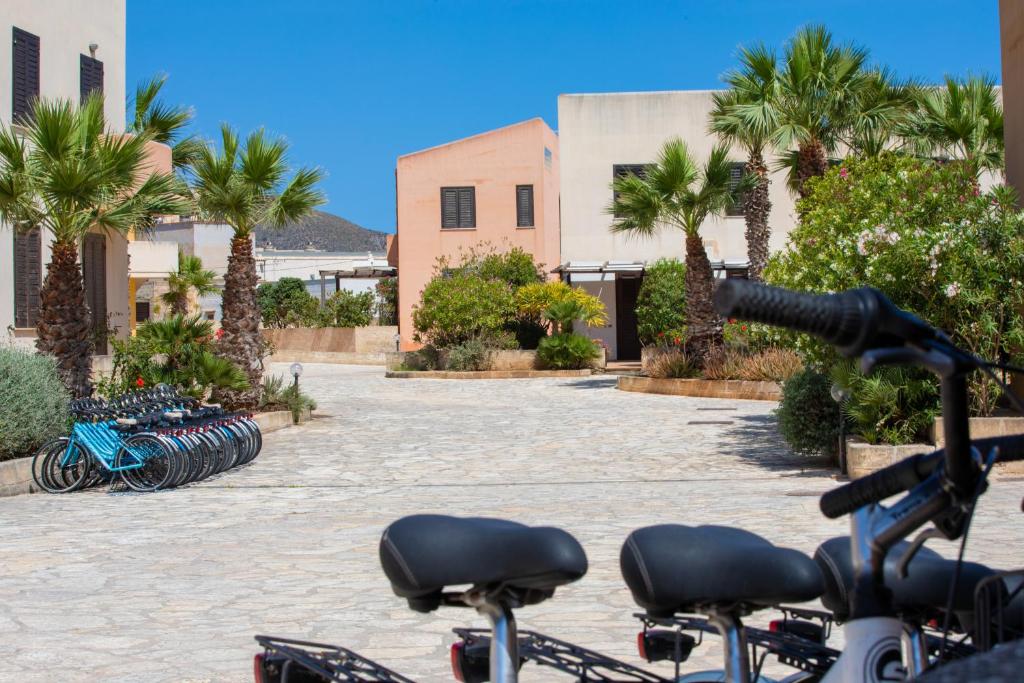 um grupo de bicicletas estacionadas num pátio com palmeiras em Elimi Favignana Apartments - Residence in città em Favignana