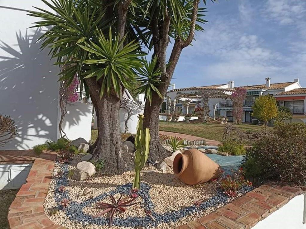 un jardín con palmeras y un sombrero en el suelo en Le joyau Andalou, en Estepona