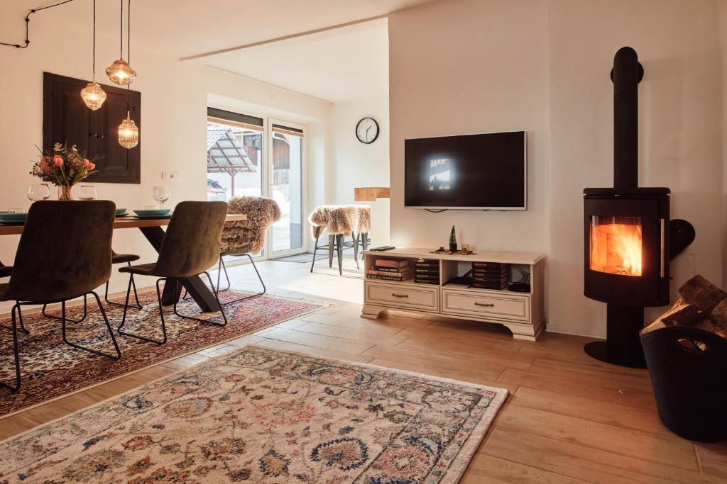 a living room with a fireplace and a table with chairs at AVA HOUSE in Podkoren