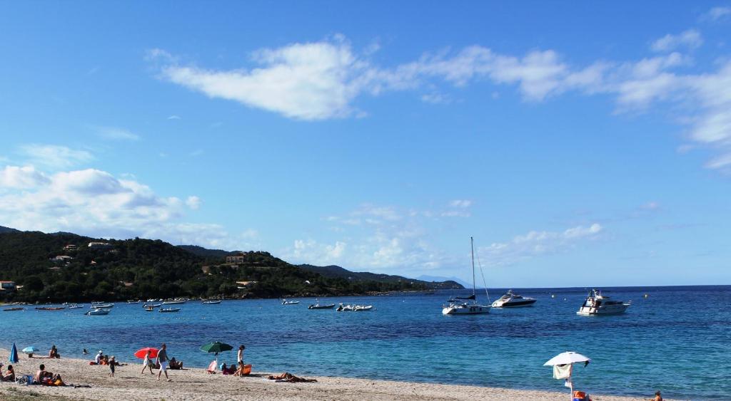 a group of people on a beach with boats in the water at Playa del Oro in Favone