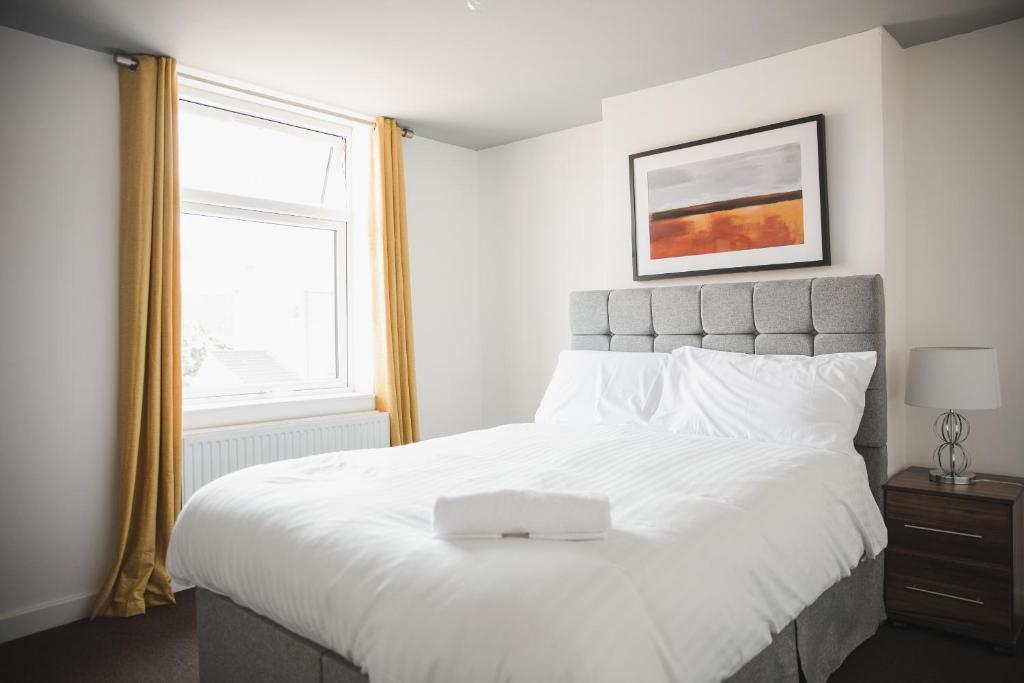 Un dormitorio con una gran cama blanca y una ventana en Riverside park house en Leicester
