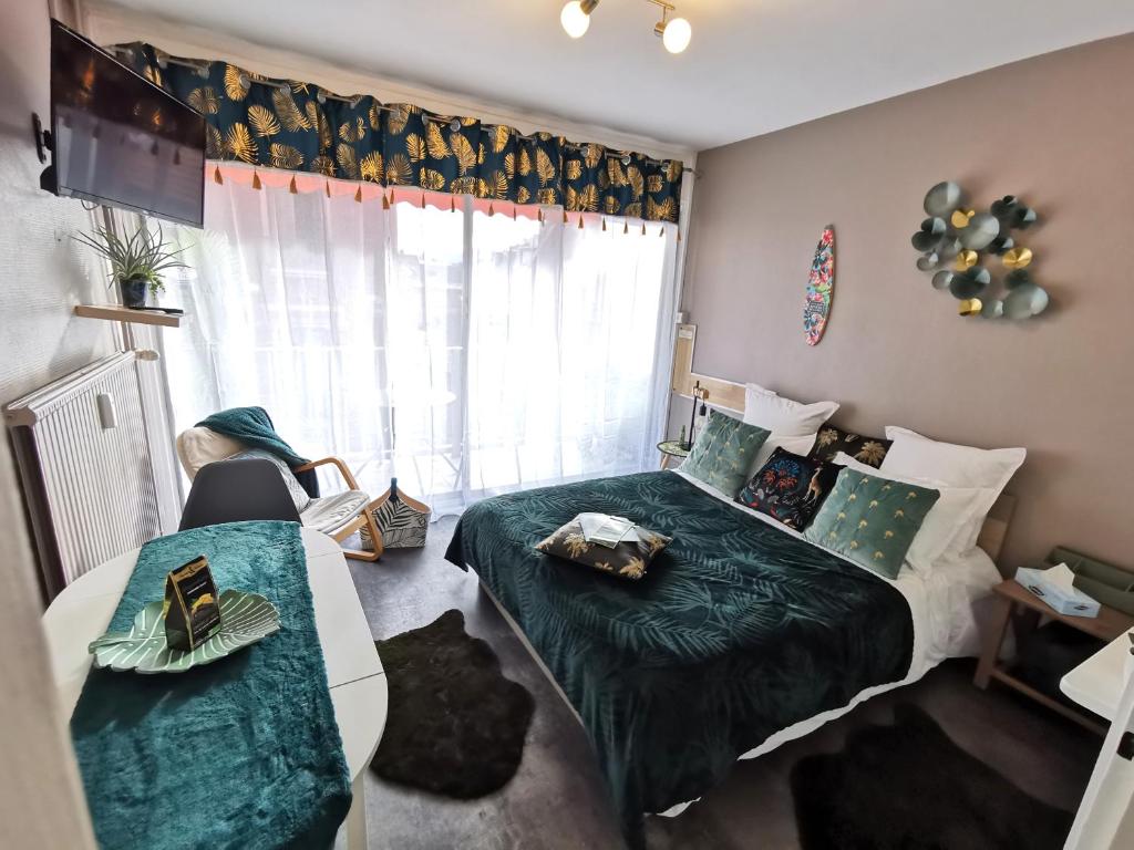 1 dormitorio con cama, mesa y ventana en L'Aixotique en Aix-les-Bains