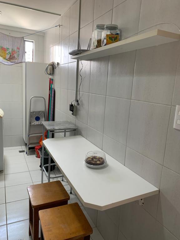 a small kitchen with a white counter and chairs at Apartamento Manaíra pertinho do Mar in João Pessoa