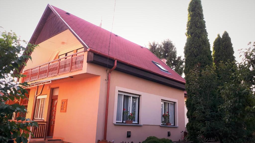 a house with a red roof and a balcony at Nárcisz Vendégház in Mezőkövesd