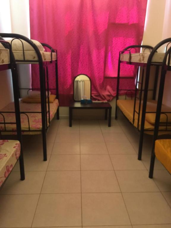 um quarto com três beliches em frente a uma cortina rosa em LADIES ONLY-AnaRuby Backpackers - Metro Station Mashreq em Dubai