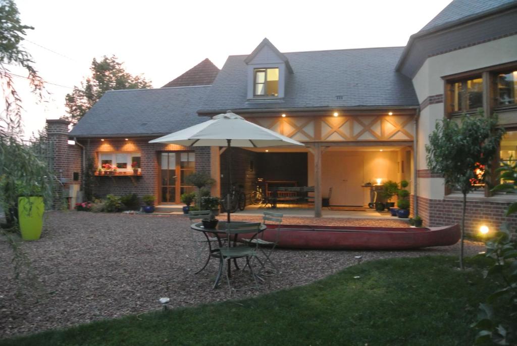 a house with a patio with a table and an umbrella at Comme une parenthèse au coeur des hortillonnages in Amiens