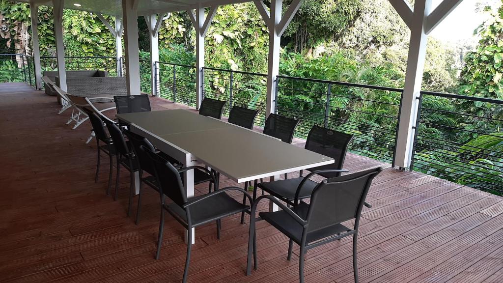 a table and chairs sitting on a deck with at Les Gîtes de la Lézarde in Petit-Bourg