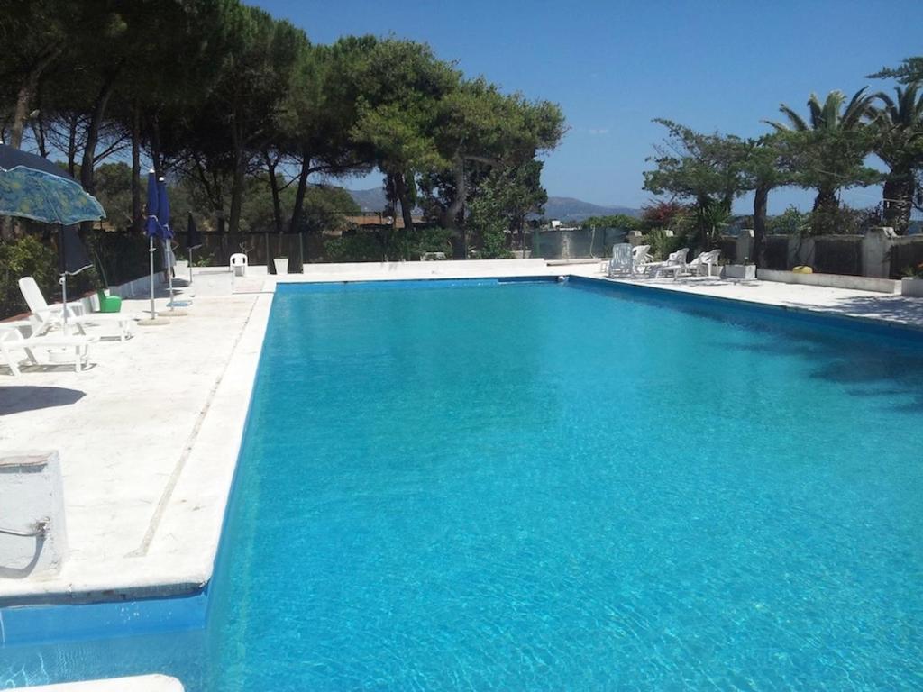 una gran piscina azul con sillas y sombrillas en Deliziosa Villa 150 metri dal mare, en Quartu SantʼElena