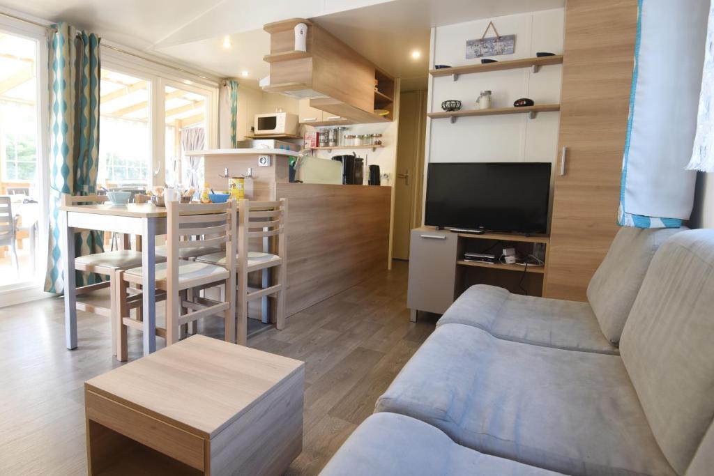 uma sala de estar com um sofá e uma mesa em Mobil Home 8 personnes em Les Mathes