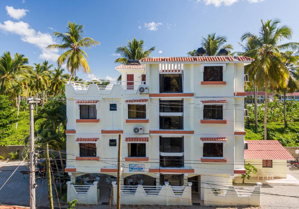 un edificio blanco con palmeras en el fondo en Hotel Turístico Marian en Las Terrenas