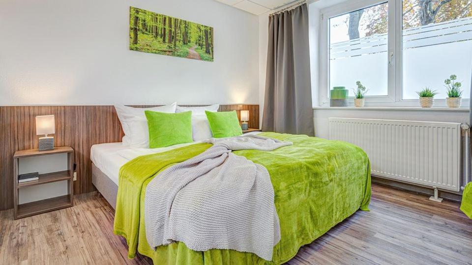 a bedroom with a bed with green sheets and a window at Hotel Stadt Mühlhausen in Mühlhausen