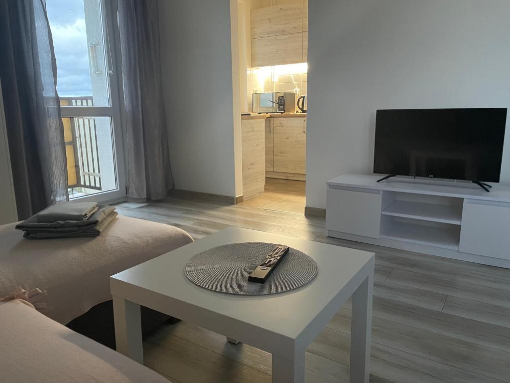 a living room with a television and a remote control on a table at Apartament Centrum in Koszalin