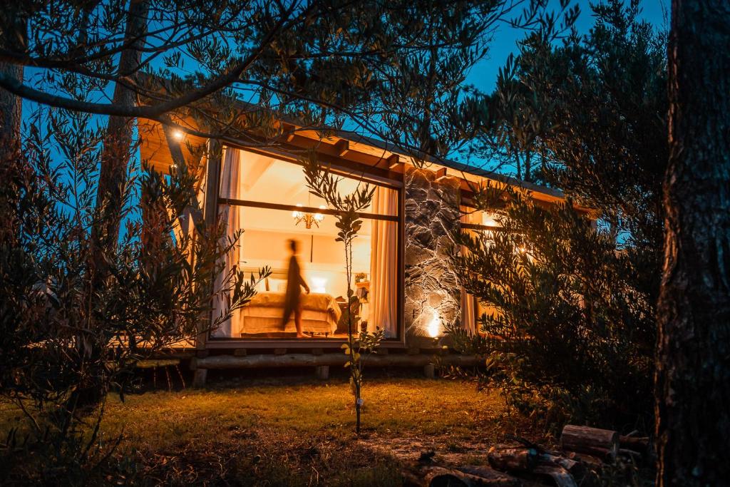 una casa en el bosque por la noche con luces en Bella Bungalows en Punta Del Diablo