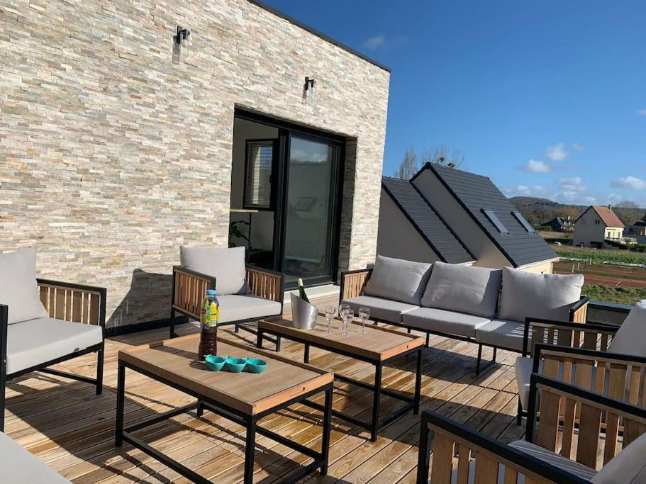 un patio avec des canapés et des tables ainsi qu'un mur en briques dans l'établissement Villa moderne Houlgataise/Roof top/proche mer !, à Houlgate