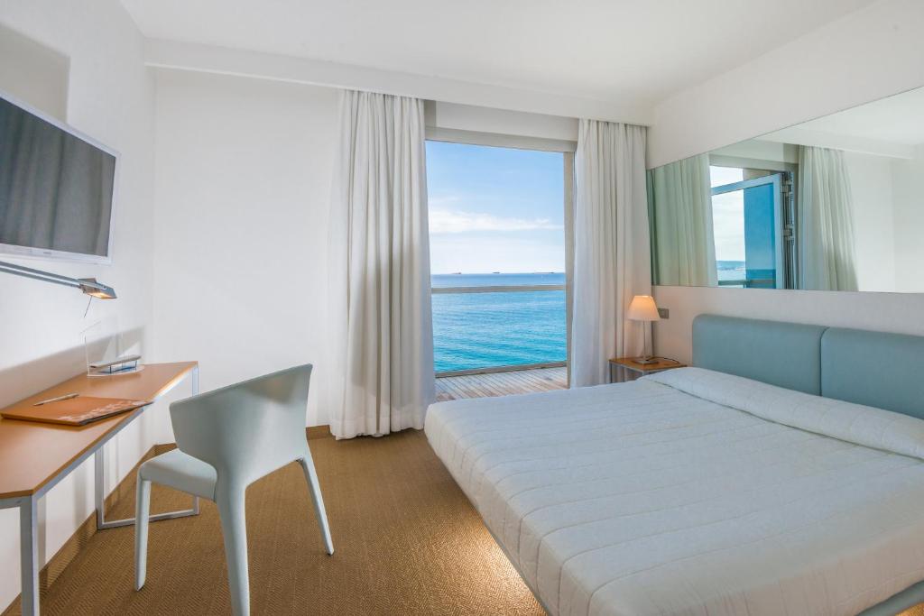 a hotel room with a bed and a desk and a window at Hotel Miramare - Adults Only in Trieste