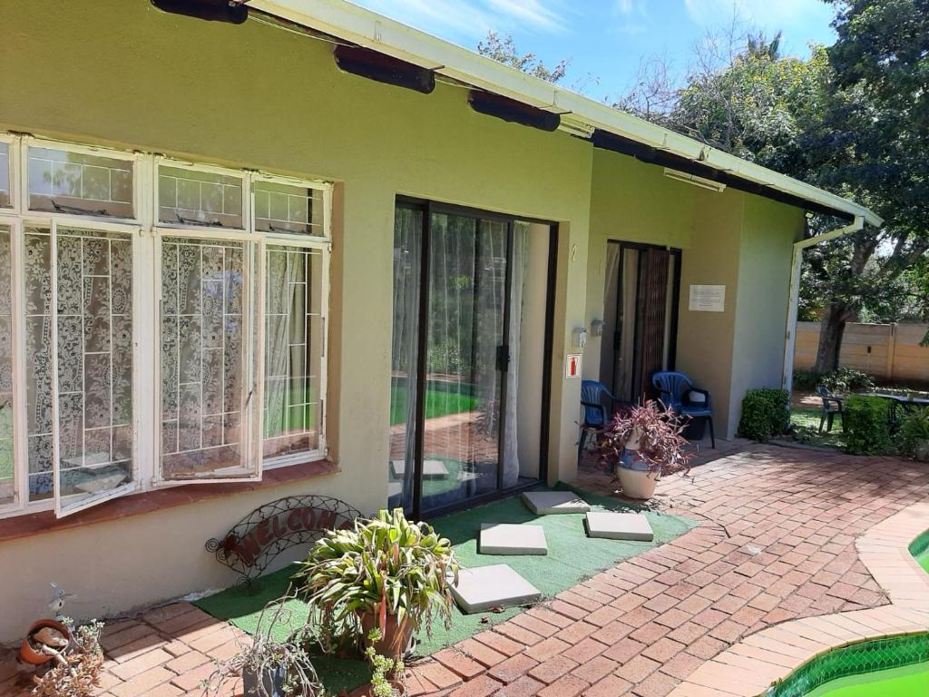 a green house with a patio with doors and windows at Chariots Guest House in Polokwane