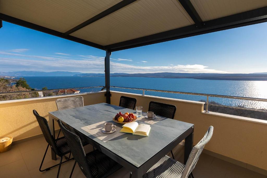 a table with a bowl of fruit on a balcony at Deluxe Apartment Stunning view in Jadranovo