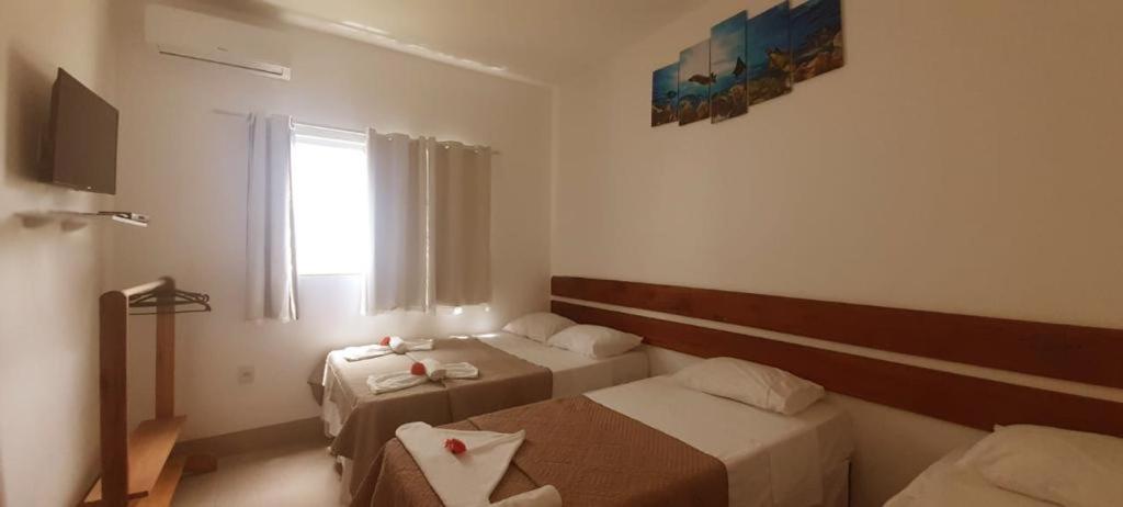 a hotel room with two beds and a window at Pousada e Casas João e Ana in Barra Grande