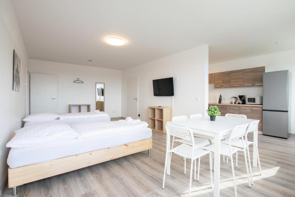 sypialnia z białym łóżkiem, stołem i krzesłami w obiekcie T&K Apartments Comfortable 3 Room Apartments with Balcony w mieście Duisburg