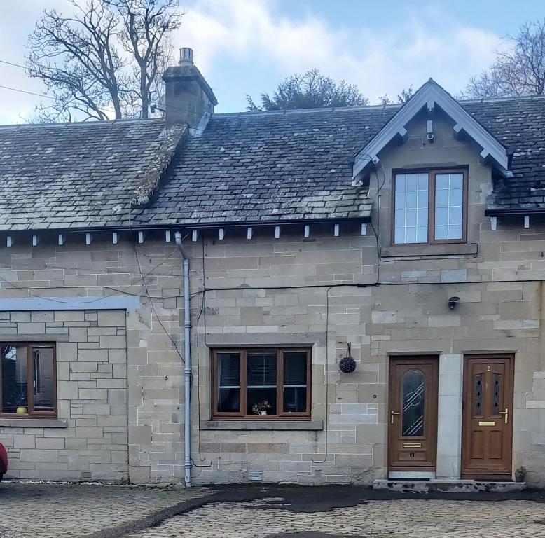 a stone house with two windows and a roof at Balnakiel Cottage, Galashiels in Torwoodlee