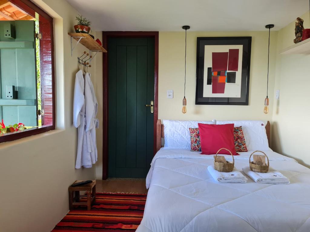 um quarto com uma cama branca e uma porta verde em Estúdio Amor: refúgio à dois nas montanhas em Lavras Novas