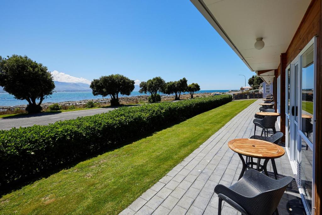 eine Terrasse mit einem Tisch, Stühlen und Meerblick in der Unterkunft Panorama Motel in Kaikoura