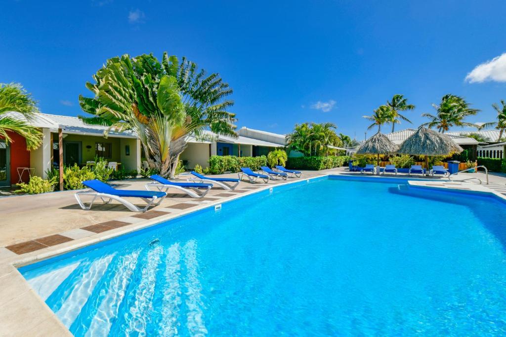 a swimming pool with blue chairs and palm trees at Aruba Blue Village Hotel and Apartments in Palm-Eagle Beach