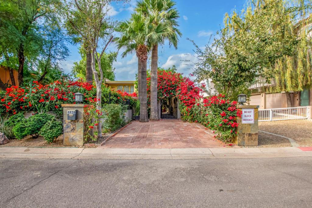 a garden with red flowers and palm trees on a street at Desert Rose Villas - Secluded One Bedroom in Old Town Scottsdale, Arizona in Scottsdale