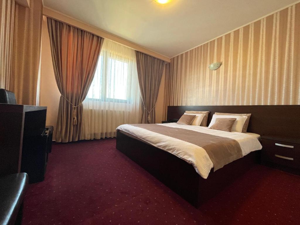 a hotel room with a large bed and a television at Hotel Athos in Bucharest