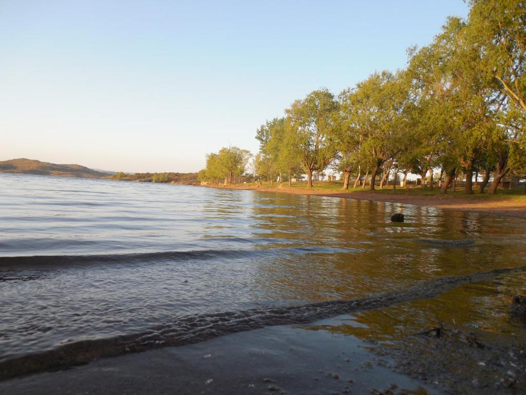 a body of water with trees and a beach at Cabaña en el lago in Trapiche