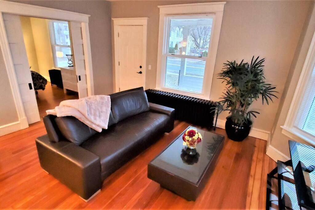uma sala de estar com um sofá de couro e uma mesa em Welcome to Hat City Danbury, A Suburban Retreat em Danbury