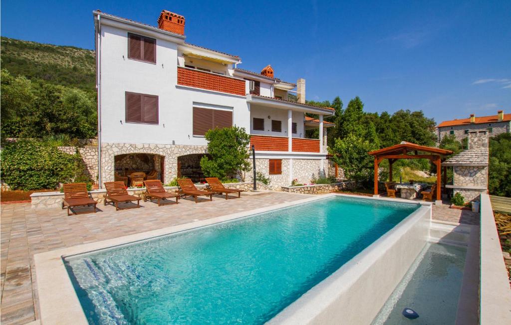 a villa with a swimming pool in front of a house at Lovely Apartment In Labin With House Sea View in Ravni